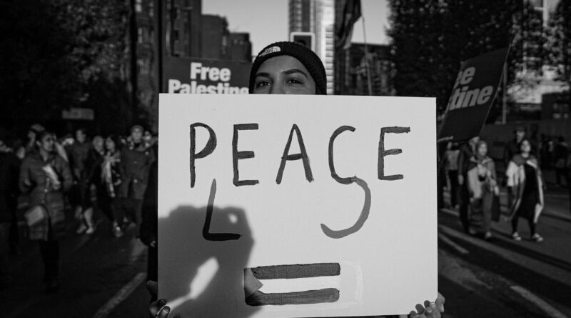 Protester in London holds up sign reading 'peace please'. Image: Alisdare Hickson, Flickr